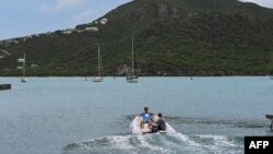 រូប​ឯកសារ៖ អ្នក​ទេសចរ​អង្គុយ​ក្នុង​ទូក​នៅ​ផែ English Harbour នៅ​ប្រទេស​អង់ទីហ្គា និង បាប៊ុយដា កាល​ពី​ថ្ងៃ​ទី​១៨ ខែ​កញ្ញា ឆ្នាំ​២០២២។