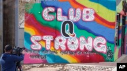 A television cameraman works near a tribute to the victims of a mass shooting at a gay nightclub painted on the side of a downtown commercial building Nov. 23, 2022, in Colorado Springs, Colo.