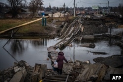 A woman crosses a destroyed bridge in Bakhmut, Donetsk region, Jan. 6, 2023, amid the Russian invasion of Ukraine.