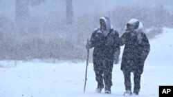 Wrightwood residents Nick and Christine Hoban enjoy a walk together as heavy snow falls on Highway 2 near Wrightwood, California, on Dec. 12, 2022. 