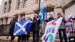 Para pengunjuk rasa membawa bendera Skotlandia di luar gedung Mahkamah Agung di London, Rabu, 23 November 2022.(AP Photo/Alberto Pezzali)