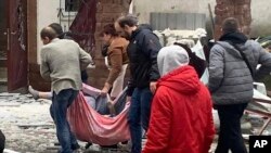 In this photo provided by the Kyiv Regional Police, people carry a body at the scene of a Russian shelling in Kyiv, Ukraine, Wednesday, Nov. 23, 2022.