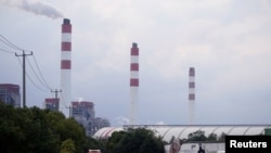 Men stand by a car near a coal-fired power plant in Shanghai, China, Oct. 21, 2021. 