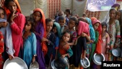 FILE - Flood victims gather to receive food in a camp, following rains and floods during the monsoon season in Sehwan, Pakistan, Sep.14, 2022. 