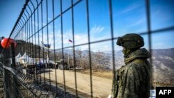 FILE - A Russian peacekeeper guards the Lachin corridor, the Armenian-populated breakaway Nagorno-Karabakh region's only land link with Armenia, as Azerbaijani environmental activists protest against what they claim the illegal mining, Dec. 27, 2022.