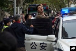 In this photo taken on Sunday, Nov. 27, 2022, a protester reacts as he is arrested by policemen during a protest on a street in Shanghai, China. (AP Photo)
