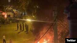 گروهی از معترضان در شهر جوانرود در استان کرمانشاه در کنار یک ماشین ماموران که در آتش می‌سوزد. یکشنبه شب، ۲۹ آبان ۱۴۰۱