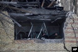 People check a tax office building that was heavily damaged in Russian shelling, in Kyiv, Ukraine, Wednesday, Dec. 14, 2022. (AP Photo/Evgeniy Maloletka)