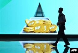 Seorang pria berdiri di dekat layar interaktif di Bursa Efek Indonesia di Jakarta, 2 Januari 2023. (Foto: Adek Berry/AFP)