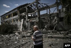 Seorang warga setempat bereaksi di depan sebuah sekolah yang hancur setelah serangan di kota Bakhmut, wilayah Donbas, Ukraina timur pada 8 Juni 2022. (Foto: AFP)