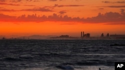 FILE - A man wades into the ocean at sunset on June 22, 2021, in Newport Beach, Calif. The National Oceanic and Atmospheric Administration said June 3, 2022, that the amount of carbon dioxide in the atmosphere in May was more than 50% higher than pre-industrial levels.