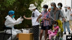 Residents line up for COVID tests, June 13, 2022, in Beijing. China's capital has put school online in one of its major districts amid a new COVID-19 outbreak linked to a nightclub.