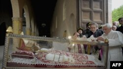 FILE - Pope Benedict XVI (R) covers the relic of Pope Celestine V with a stole during his papal visit at St. Maria of Collemaggio church collapsed on April 6 after the earthquake in L'Aquila, Apr. 28, 2009. (Photo by Osservatore Romano / Pool / AFP)