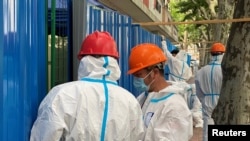 Workers in protective suits set up barriers outside a building, following the coronavirus disease (COVID-19) outbreak, in Shanghai, China, June 9, 2022. 
