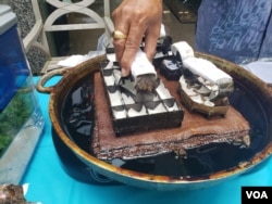 Agus Ismoyo memeragakan alat batik cap dengan lilin untuk membatik (VOA/Puspita).