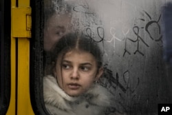 FILE - A child looks out a steamy bus window with drawings on it as civilians are evacuated from Irpin, on the outskirts of Kyiv, Ukraine, on March 9, 2022.