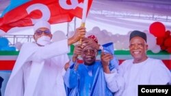Lokacin da shugaba Buhari ya ba Tinubu (tsakiya) tutar jam'iyya (Hoto: Fadar shugaban kasa).