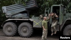在乌南尼古拉耶夫地区的前线附近，一名乌克兰女军人在丈夫兼战友的帮助下跳下BM21“冰雹”多管火箭发射车。(2022年9月16日)