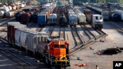 FILE- A BNSF rail terminal worker monitors the departure of a freight train, in Galesburg, Ill., June 15, 2021.