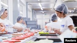 FILE - Maria, a refugee from Mylokaiv in Ukraine, decorates gingerbread Oktoberfest hearts at the 'Zuckersucht' bakery in Aschheim near Munich, Germany, May 18, 2022. 
