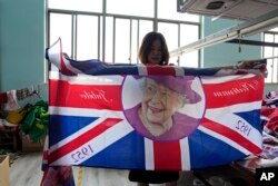 Generalna menadžerka Fan Aiping drži jednu od zastava sa fotografijom kraljice u prostoru fabrike, 16. septembra 2022.