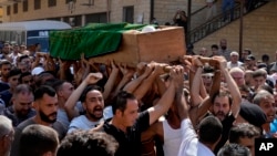 Mourners chant slogans as they carry the coffin of Palestinian Abdul-Al Abdul-Al, 24, who was on a migrant boat that sank, during his funeral in the Palestinian refugee camp of Nahr el-Bared, near the northern city of Tripoli, Lebanon, Sept. 24, 2022