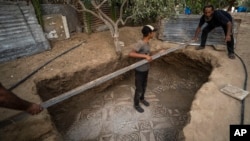 Palestinians clean around a Byzantine-era mosaic floor that was uncovered recently by a farmer in Bureij in central Gaza Strip, Sept. 5, 2022. (AP Photo/Fatima Shbair)