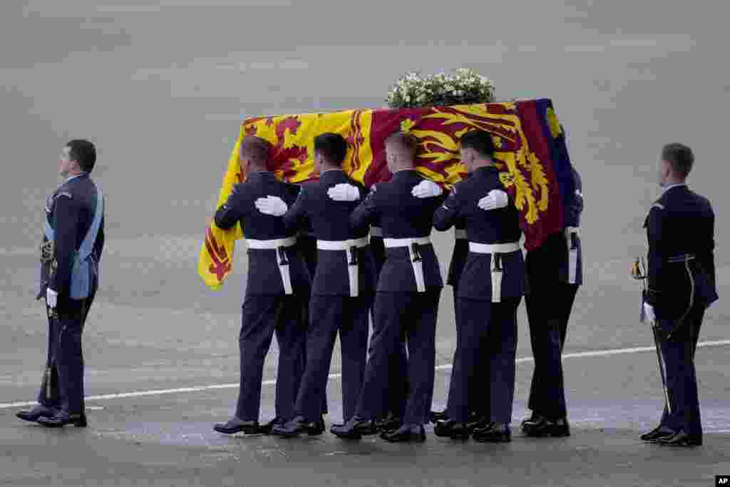 The coffin of Queen Elizabeth II is carried off a plane by the Queen's Colour Squadron at RAF Northolt in London, to be taken to Buckingham Palace, Sept. 13, 2022. 