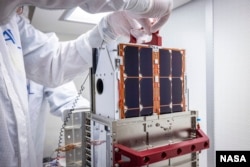 DART team engineers lift and inspect the LICIACube CubeSat after it arrived at the Johns Hopkins Applied Physics Laboratory (APL) in Laurel, Maryland in August. The miniaturized satellite will deploy 10 days before DART's asteroid strike. (Image Credits: