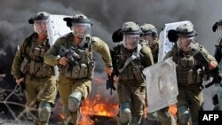 Pasukan keamanan Israel berlari ke arah demonstran Palestina selama bentrokan menyusul protes terhadap pengambilalihan tanah Palestina oleh Israel di desa Kfar Qaddum di Tepi Barat (23/9). 