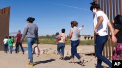 FILE - Brazilian migrants make their way around a gap in the U.S.-Mexico border in Yuma, Ariz., seeking asylum in the U.S. after crossing over from Mexico, June 8, 2021. 
