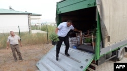 Bayram Mamedov unloads a truck with belongings as he and his family settle in their new house as they return to the newly rebuilt village of Agali in the district of Zangilan, Azerbaijan, July 19, 2022.