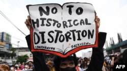 Seorang pengunjuk rasa memegang plakat dalam aksi demo bertepatan dengan pidato kenegaraan pertama Presiden Filipina Ferdinand Marcos Jr, di Quezon City, pinggiran kota Manila, 25 Juli 2022. (Ted ALJIBE / AFP)
