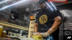 Ilustrasi - Alex Batista, salah satu pemilik toko makanan Deli-licious di wilayah Queens, New York, 6 April 2020, membuat sandwich di tokonya. (AP/Bebeto Matthews)