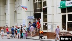 지난 7월 우크라이나 남부 헤르손 시내 관공서 입구에서 러시아 시민권을 신청하려는 주민들이 줄지어 차례를 기다리고 있다. 건물 외벽에는 러시아 국기가 게양돼있다. (자료사진)