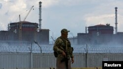 ARHIVA - Vojnik sa ruskom zastavom na borbenom prsluku stražari ispred nuklearne elektrane Zaparožje, tokom napada Rusije na Ukrajinu, 4. avgusta 2022.