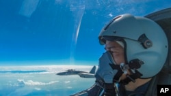 In this photo released by Xinhua News Agency, an air force pilot from the Eastern Theater Command of the Chinese People's Liberation Army (PLA) looks as they conduct a joint combat training exercises around the Taiwan Island on Sunday, Aug. 7, 2022. (Wang Xinchao/Xinhua via AP)