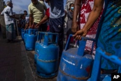 People wait in a queue with empty cylinders to buy domestic gas at a distribution center, in Colombo, Sri Lanka, July 12, 2022.