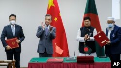 Chinese Foreign Minister Wang Yi, center left, and his Bangladeshi counterpart A.K. Abdul Momen applaud as both countries sign agreements in Dhaka, Bangladesh, Aug.7, 2022