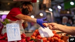 FILE - A customer pays for vegetables at the Maravillas market in Madrid, on May 12, 2022.