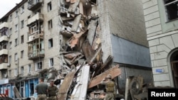 Prajurit Ukraina berdiri di depan flat Valentina Popovichuk, di Kharkiv, Ukraina, 11 Juli 2022. (Foto: Reuters)