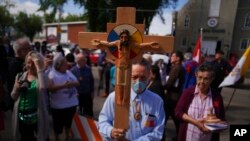 Elmer Waniandy raises the crucifix as he leads his fellow parishioners into the renovated Sacred Heart Church of the First Peoples sanctuary, July 17, 2022, in Edmonton, Alberta. Pope Francis will meet with parishioners at Sacred Heart during his visit to the Canadian province.