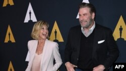 FILE - Actors Olivia Newton-John and John Travolta dance on the red carpet as they arrive for the 40th anniversary celebration of the movie "Grease" at the Academy of Motion Picture Arts and Sciences in Beverly Hills, California, Aug. 15, 2018.