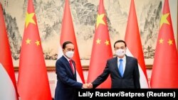 Presiden Joko Widodo berjabat tangan dengan Perdana Menteri China Li Keqiang dalam pertemuan mereka di Beijing, China, 26 Juli 2022. (Foto: via Reuters)