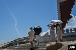 Jejak asap proyektil militer China terlihat di langit saat turis melihat dari Pulau Pingtan, salah satu titik terdekat China daratan dari Taiwan, di Fujian pada 4 Agustus 2022. (Foto: AFP)