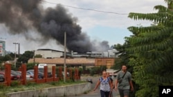 Orang-orang berjalan di jalan saat asap mengepul di udara setelah serangan di Odessa, Ukraina, Sabtu, 16 Juli 2022. (AP/Nina Kolyachonok)