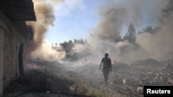 乌克兰一名救援人员在顿涅茨克地区托列茨克镇被俄军炸毁的住宅区废墟中行走。（2022年7月27 日）