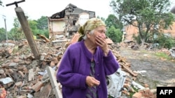 Seorang perempuan lansia warga setempat, Raisa Kuval (82 tahun), menangis saat menyaksikan sebuah bangunan yang hancur akibat tembakan artileri di kota Chuguiv, Kharkiv, Ukraina timur laut, 16 Juli 2022. (Foto: ilustrasi/ AFP) 