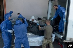 Servicemen and workers carry bodies of servicemen killed during the siege of Mariupol into the city morgue in Kyiv, Ukraine, July 21, 2022.