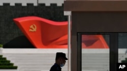 Seorang aparat berdiri di dekat patung bendera Partai Komunis China di Museum Partai Komunis China pada 26 Mei 2022, di Beijing. (Foto: AP)